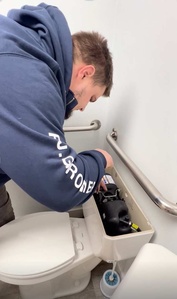 Plumber installing or repairing a toilet