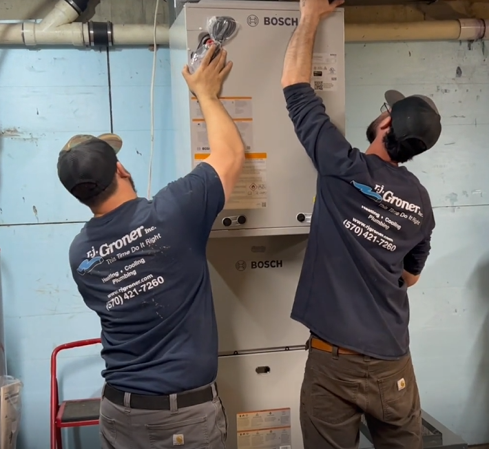 Technicians installing a wall-mounted cooling unit